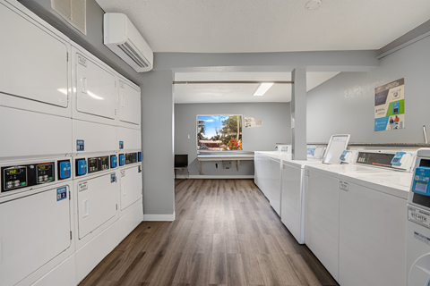 a laundry room with washes and dryers and a counter with a window